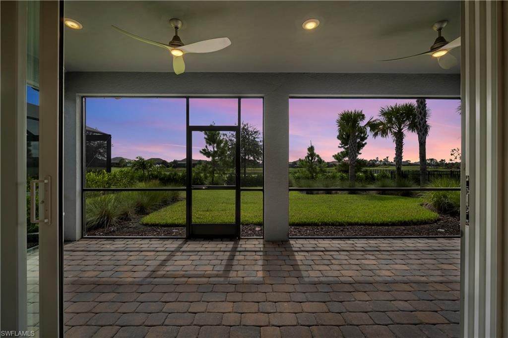 Screened-in patio featuring paver flooring, recessed lighting, and dual ceiling fans