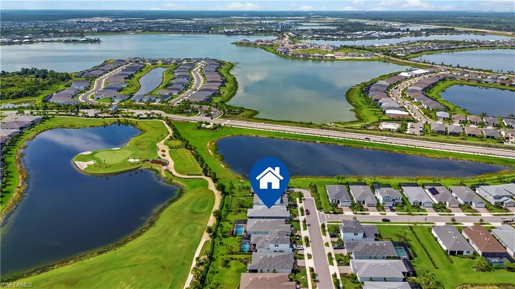 Aerial perspective of a developed residential area with multiple bodies of water, golf course, and a paved street