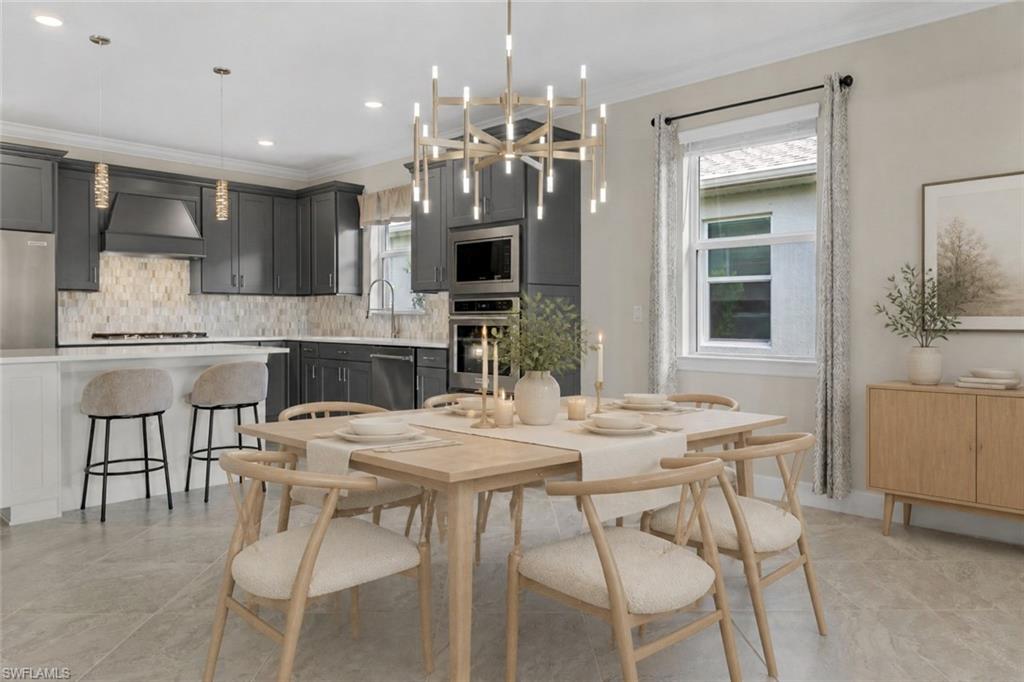 Open-concept dining area with a modern chandelier, light wood-finish flooring, and a kitchen featuring dark cabinetry, stainless steel appliances, and a tiled backsplash