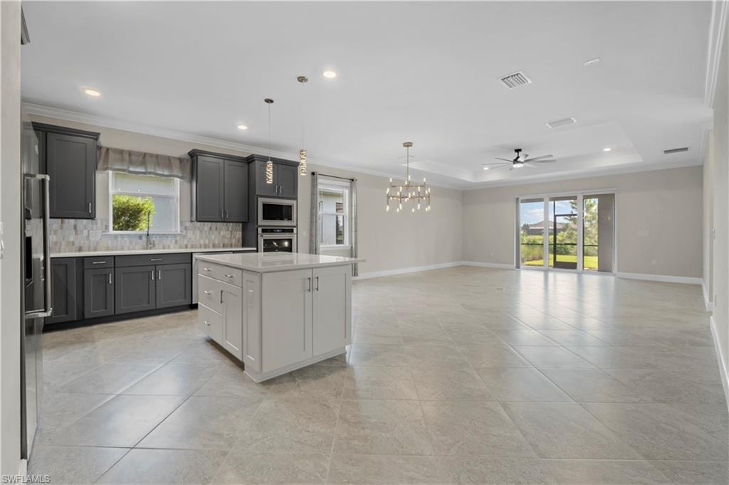 Open-concept kitchen and living area featuring a central island, recessed lighting, and a tray ceiling