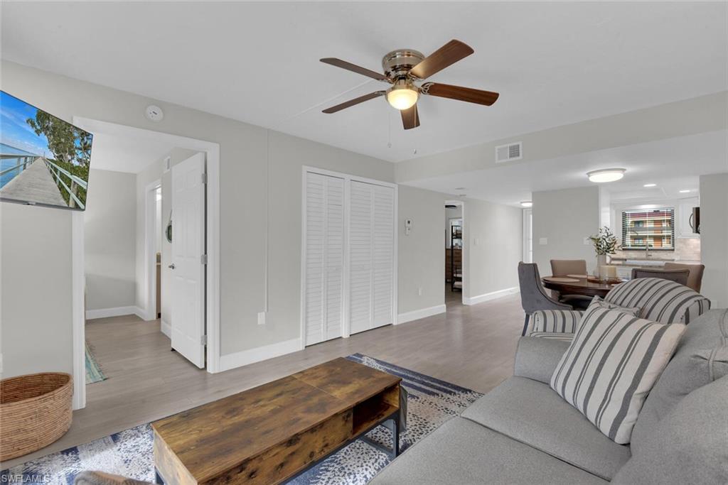 Light wood-finish flooring, ceiling fan with integrated lighting, white bifold closet doors, recessed lighting, and a kitchen with white cabinetry