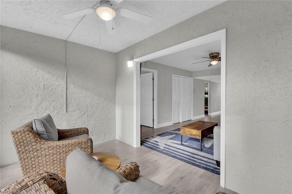 Textured wall finish, ceiling fan with integrated lighting, wood-finish flooring, white trim details, white interior doors