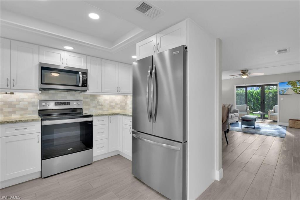 Kitchen featuring stainless steel appliances, white cabinetry, tile backsplash, granite countertops, and recessed lighting