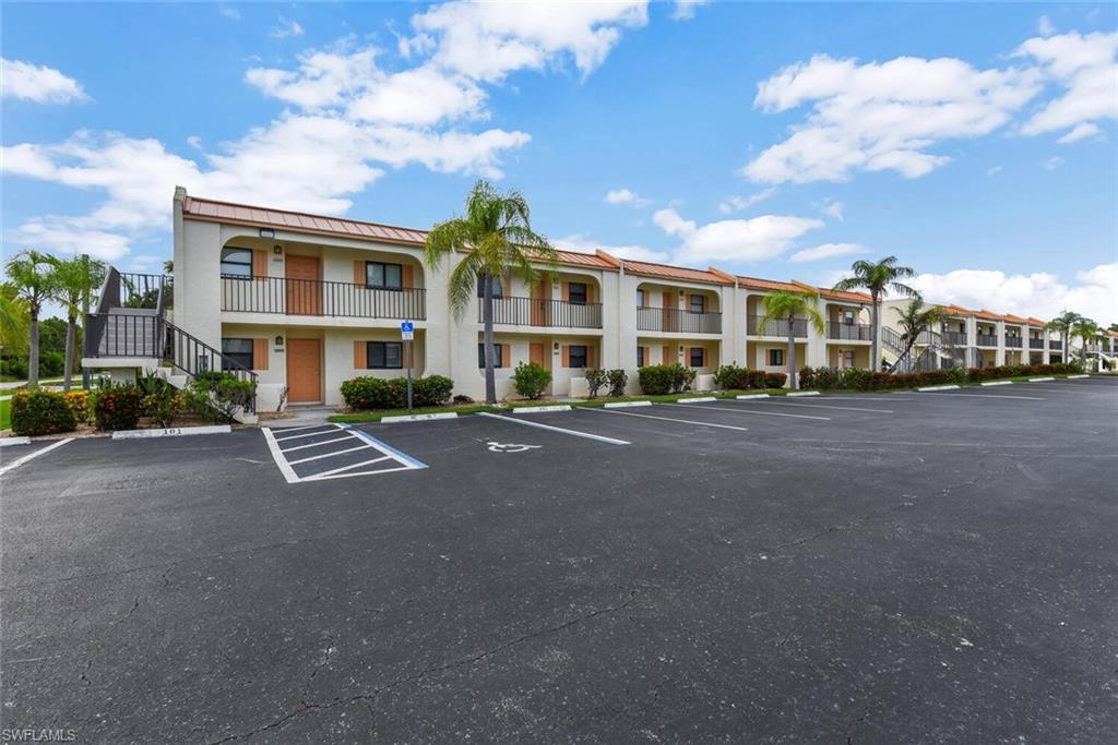 Multi-unit property with stucco exterior, tile roofing, private balconies, and a paved parking area