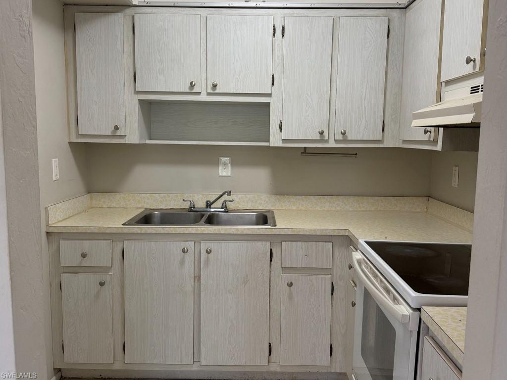 Kitchen featuring light-finish cabinetry, a double basin sink, and an electric range