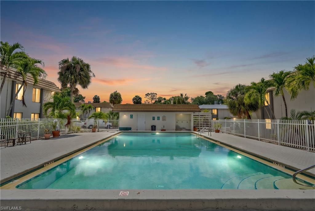 Rectangular swimming pool with integrated steps, surrounded by a paved deck and white fencing