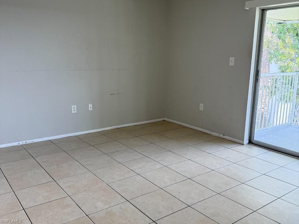 Neutral-toned tile flooring, light gray wall finishes, and a sliding glass door providing access to an outdoor balcony with white railings