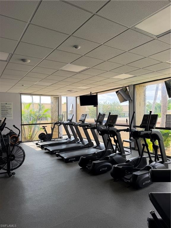 Fitness center with rubber flooring, large windows, and a grid ceiling