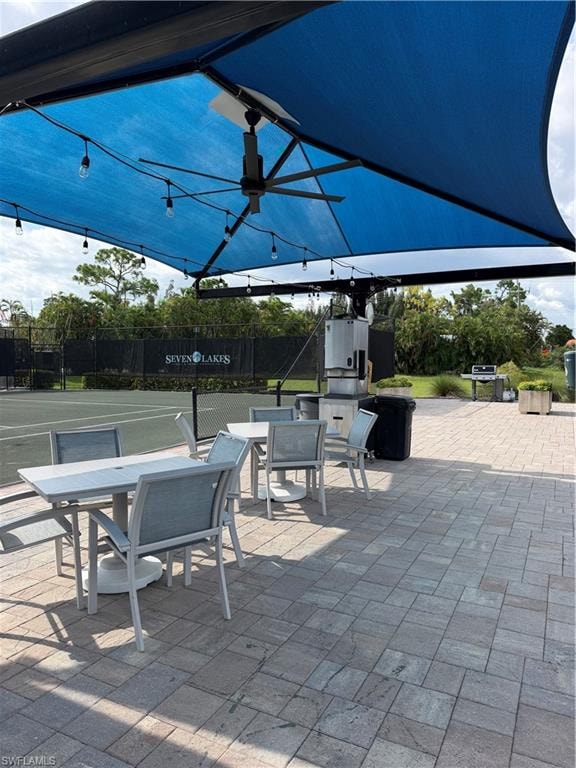 Paved patio area featuring shaded seating, string lighting, and an overhead fan