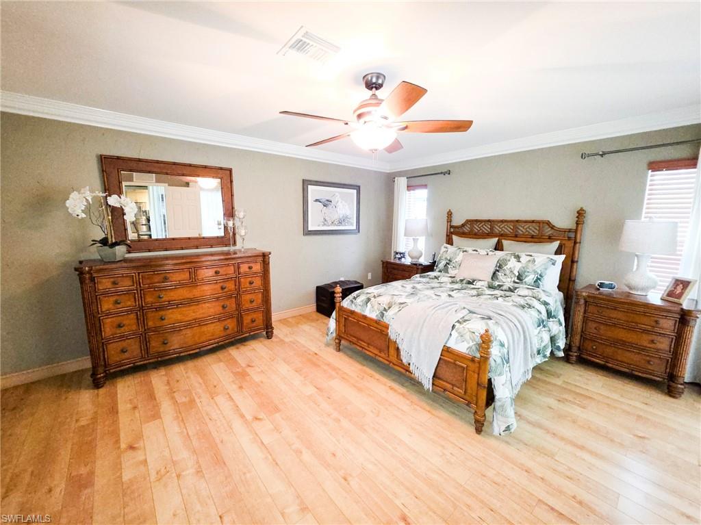 Hardwood flooring throughout, crown molding, ceiling fan with integrated lighting, and two windows with white blinds