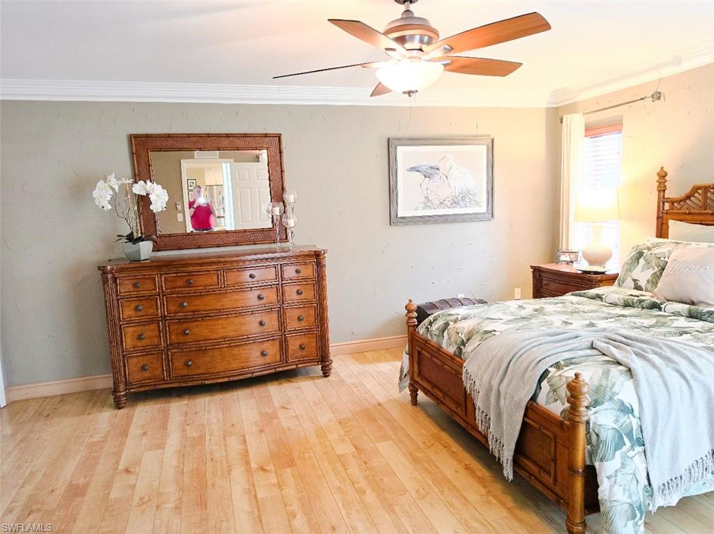 Crown molding, wood-finish flooring, ceiling fan with integrated lighting, and window with blinds