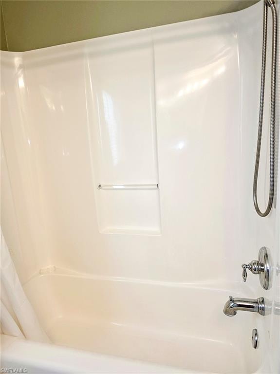 White acrylic tub with integrated shower surround, chrome fixtures, and a handheld showerhead