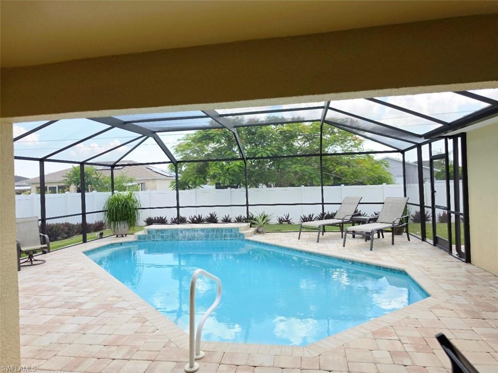 Screen-enclosed pool featuring a paver patio and an integrated spa with a waterfall element