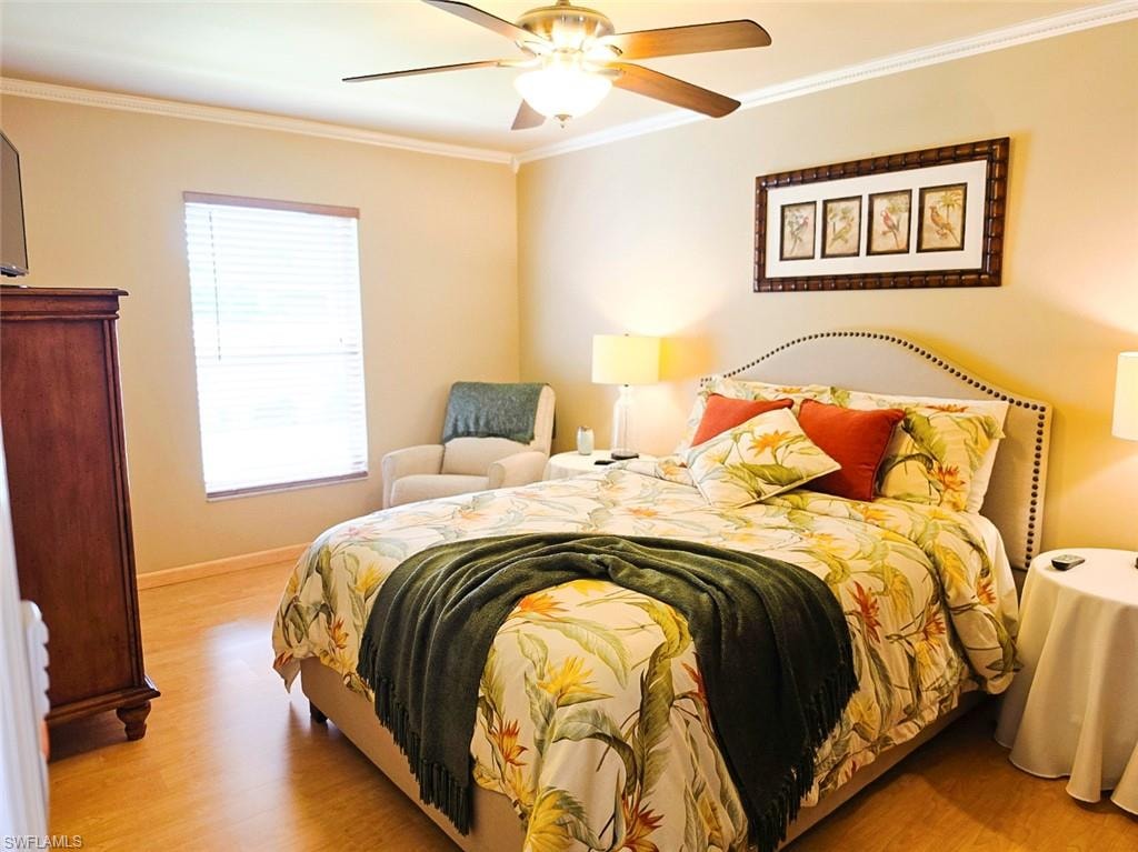 Wood-finish flooring, crown molding, ceiling fan with integrated lighting, and a window with blinds