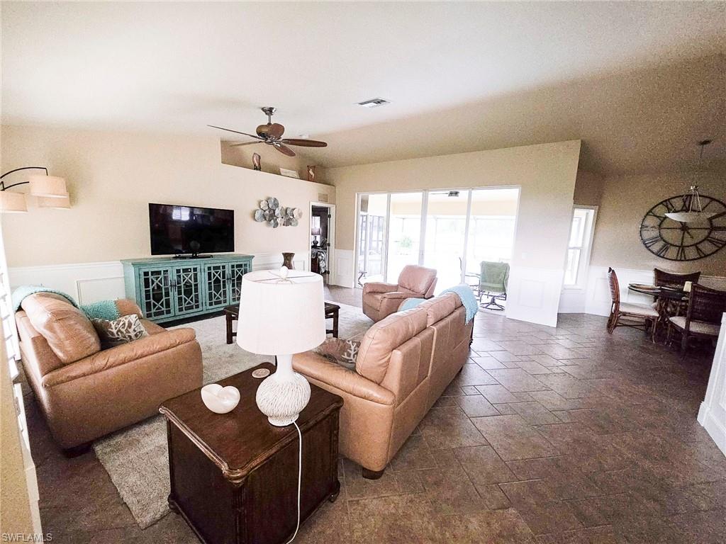 Spacious living area featuring tile flooring, a decorative wainscoting accent, and a built-in media console