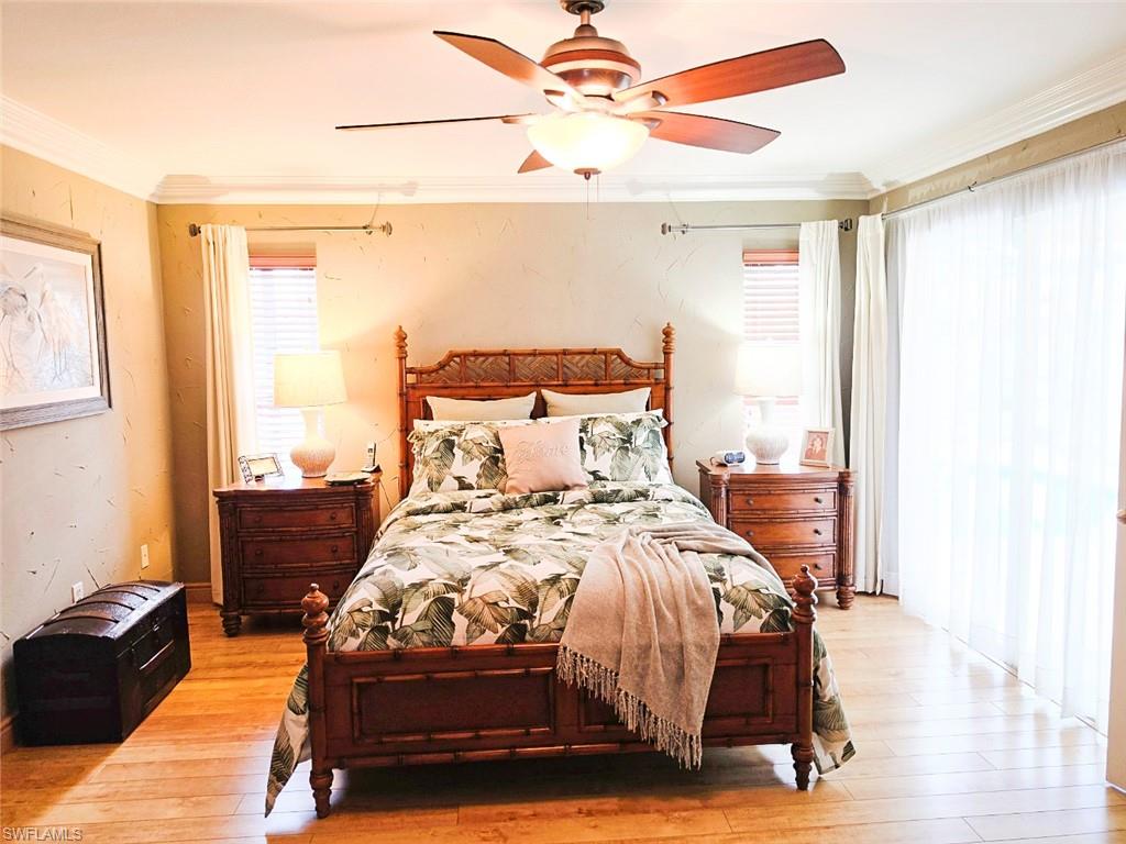 Wood-finish flooring, crown molding, ceiling fan with integrated lighting, and a window with blinds and drapes