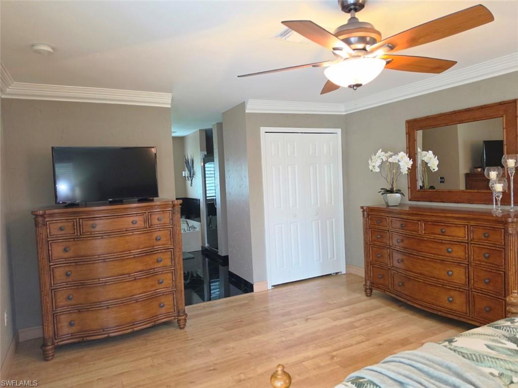 Wood-finish flooring, ceiling fan with integrated lighting, crown molding, white bi-fold closet doors