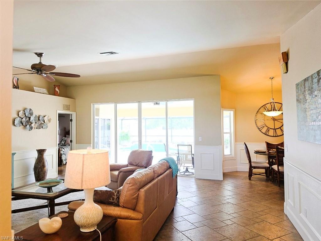 Tiled flooring throughout, ceiling fan, white paneled wainscoting, sliding glass doors, and recessed lighting