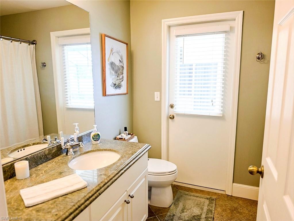 Dual vanity with undermount sinks, stone countertop, white shaker-style cabinetry, and large wall-mounted mirror