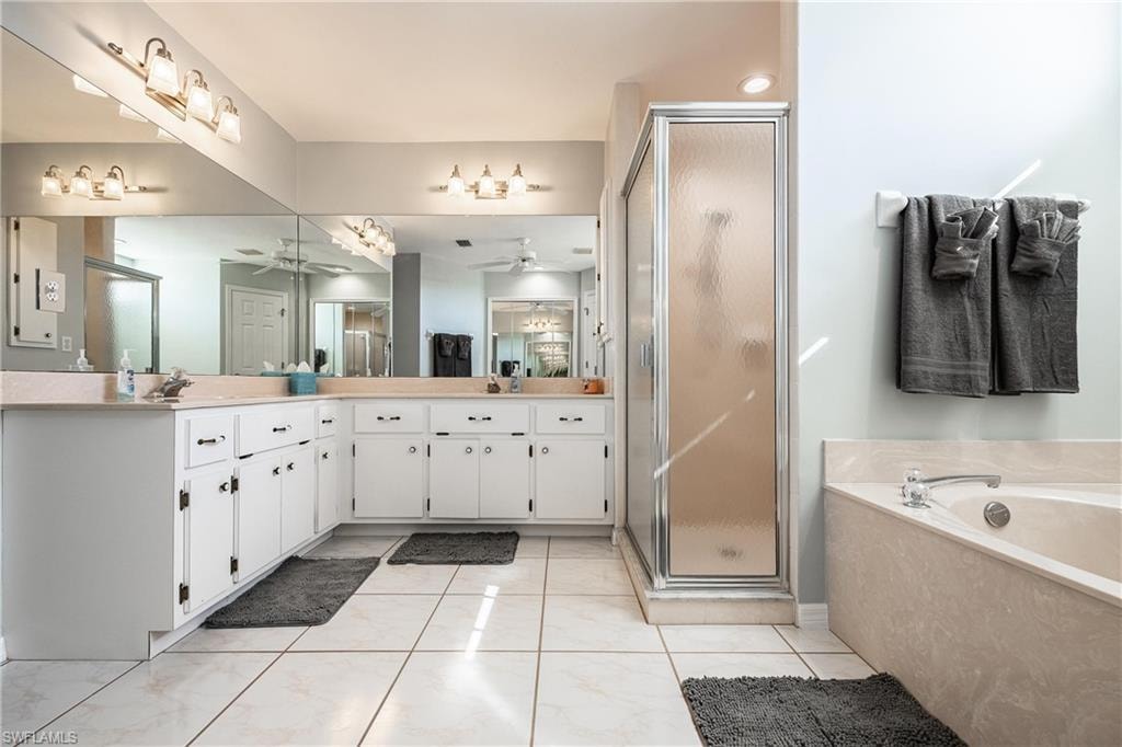 Full bath with vanity, a garden tub, a stall shower, and ceiling fan