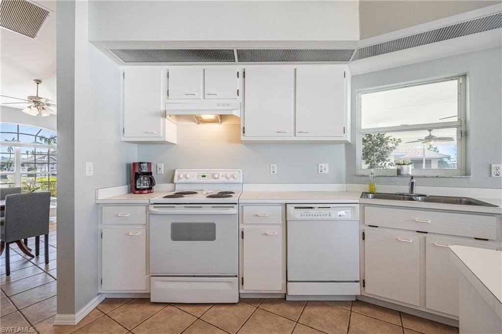 Kitchen with under cabinet range hood, a ceiling fan, visible vents, and white appliances