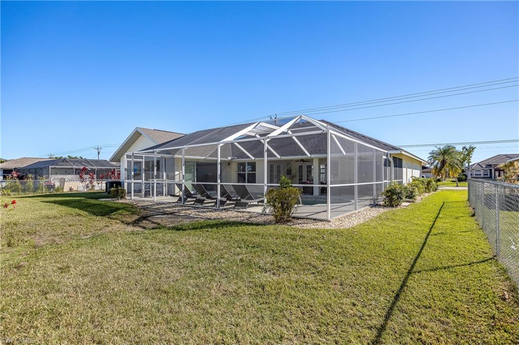 Rear view of property featuring a fenced backyard, a lanai, a patio area, and a lawn