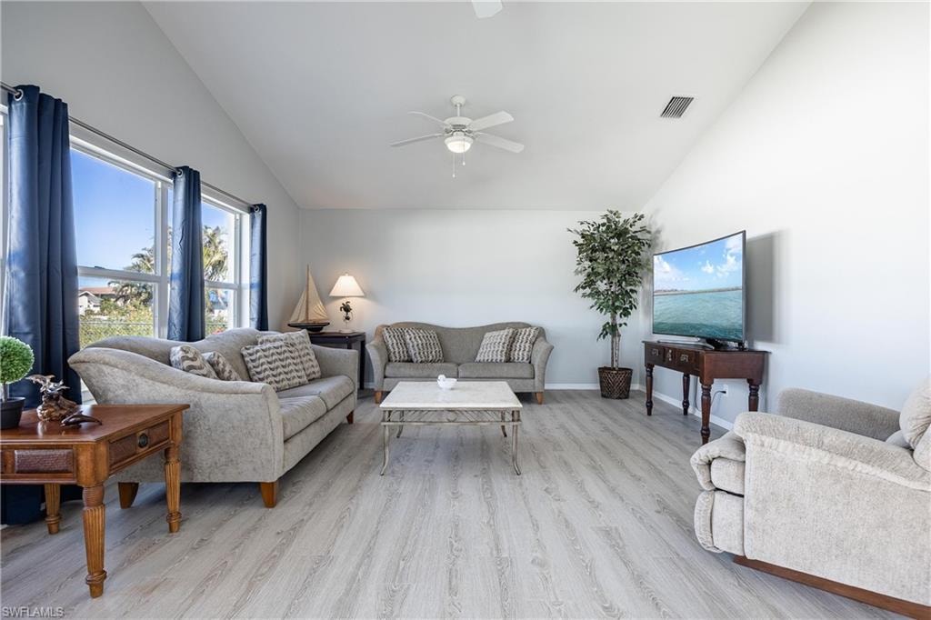 Living room featuring visible vents, light wood-style floors, baseboards, high vaulted ceiling, and ceiling fan