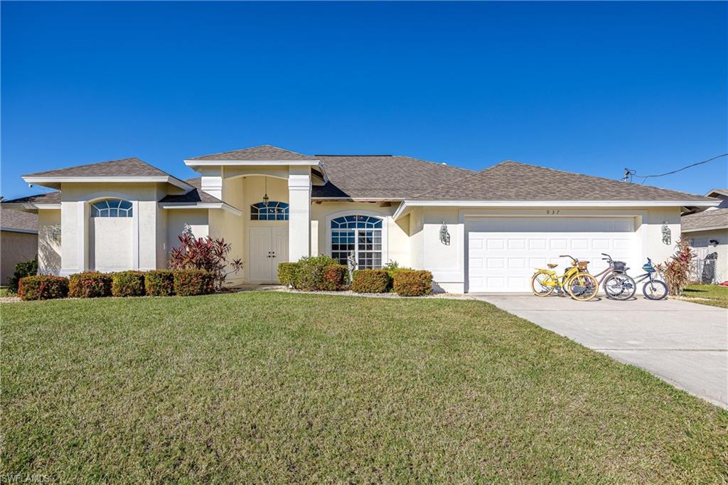 View of front facade with stucco siding, a front lawn, driveway, and a garage
