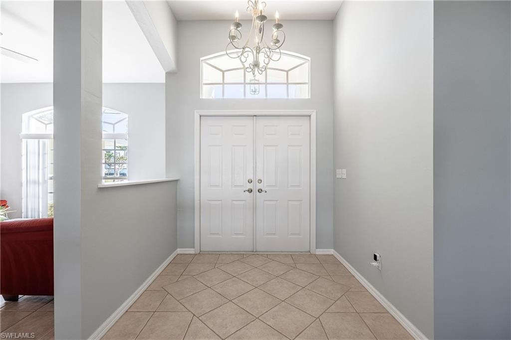 Foyer entrance with a chandelier, baseboards, and light tile patterned floors