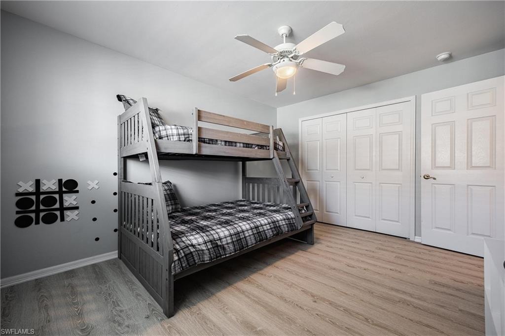 Bedroom with baseboards, a ceiling fan, wood finished floors, and a closet