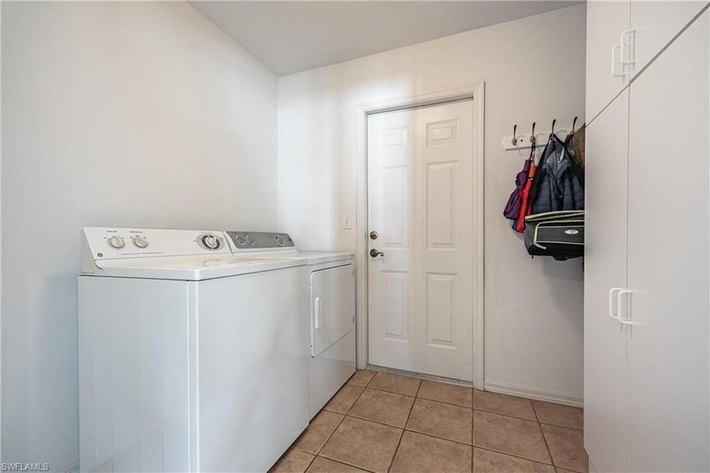 Laundry area featuring washer and dryer, baseboards, cabinet space, and light tile patterned floors