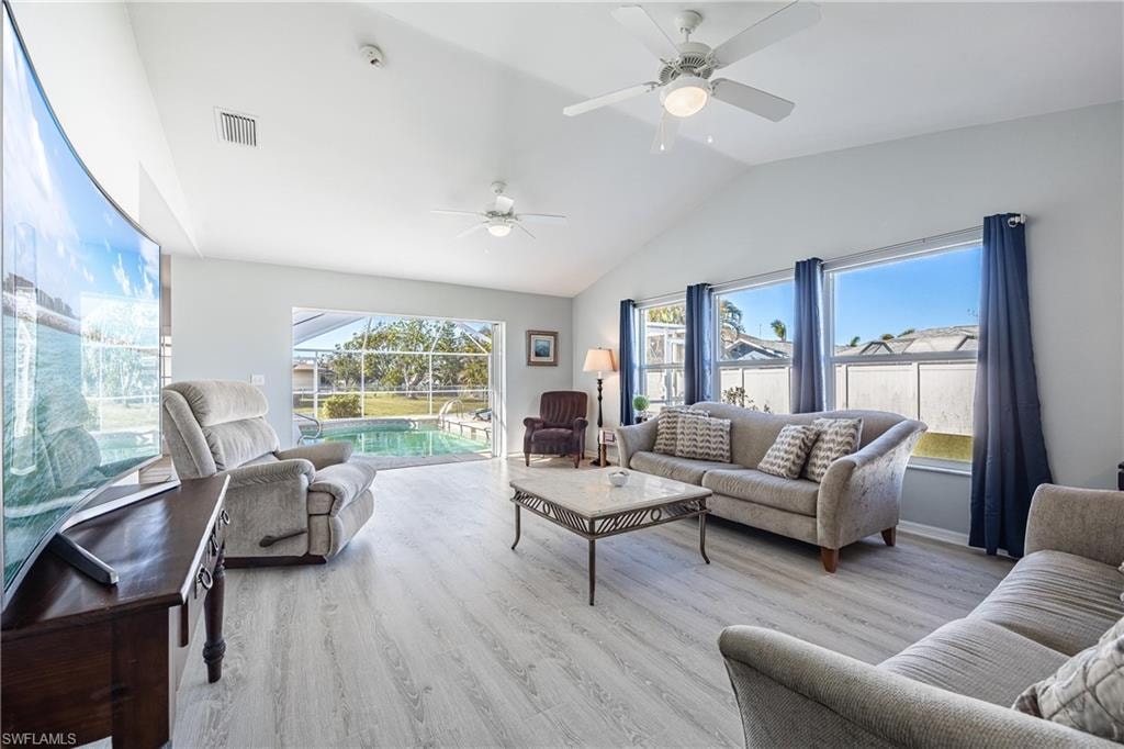 Living room with ceiling fan, lofted ceiling, wood finished floors, and visible vents