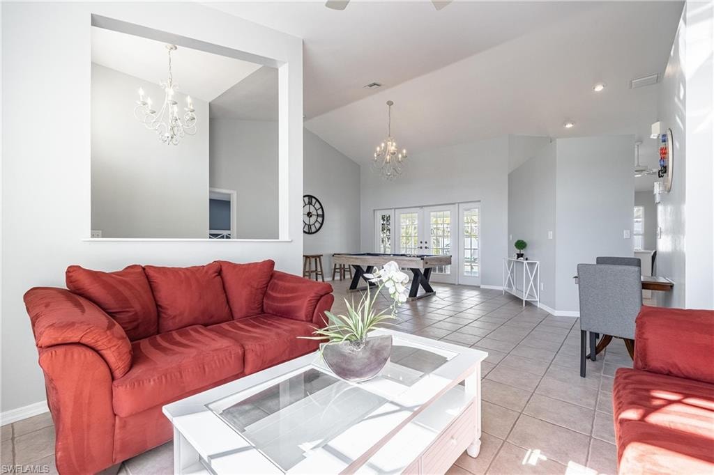 Living room featuring light tile patterned flooring, baseboards, a notable chandelier, and french doors