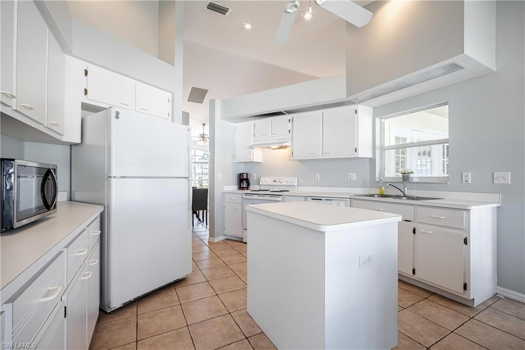 Kitchen featuring under cabinet range hood, a ceiling fan, white appliances, and a sink