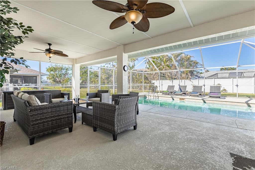 View of patio with a fenced in pool, a lanai, fence, ceiling fan, and an outdoor living space