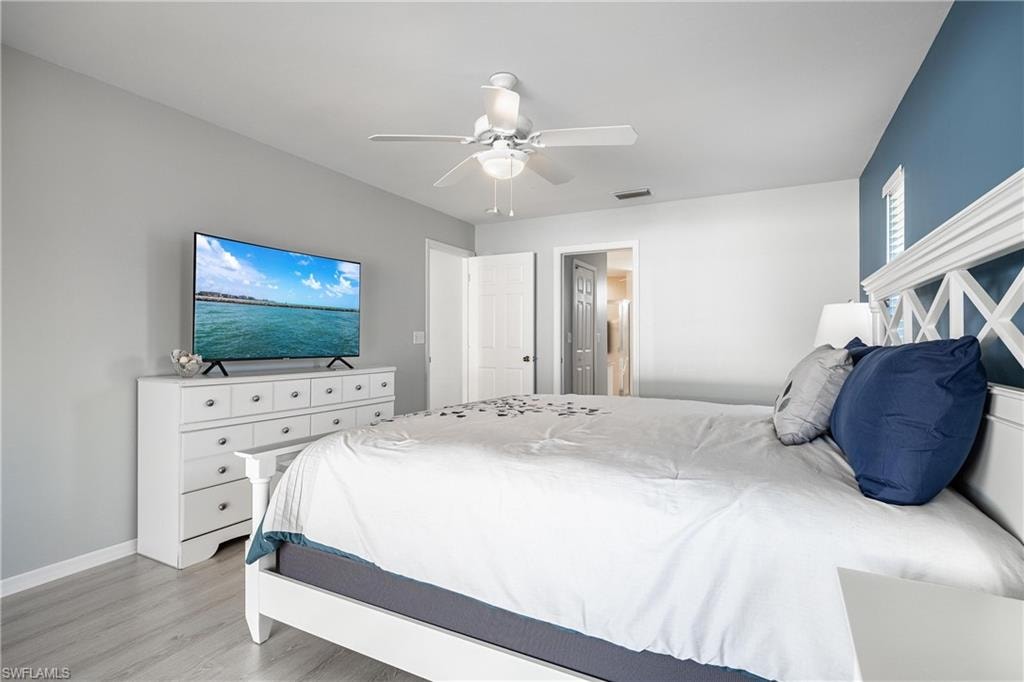 Bedroom with light wood-type flooring, visible vents, baseboards, and ceiling fan