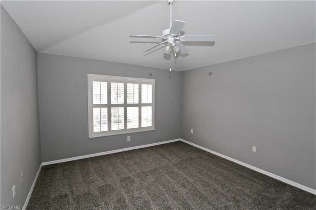 Vaulted ceiling with a ceiling fan, window with plantation shutters, and carpeted flooring