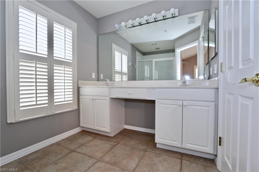 Dual vanity with white cabinetry and integrated sinks, large wall-mounted mirror, and tile flooring