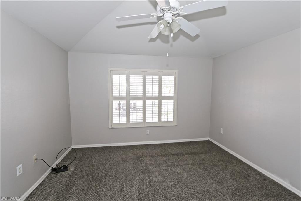 Recessed window with white plantation shutters, vaulted ceiling, and overhead ceiling fan