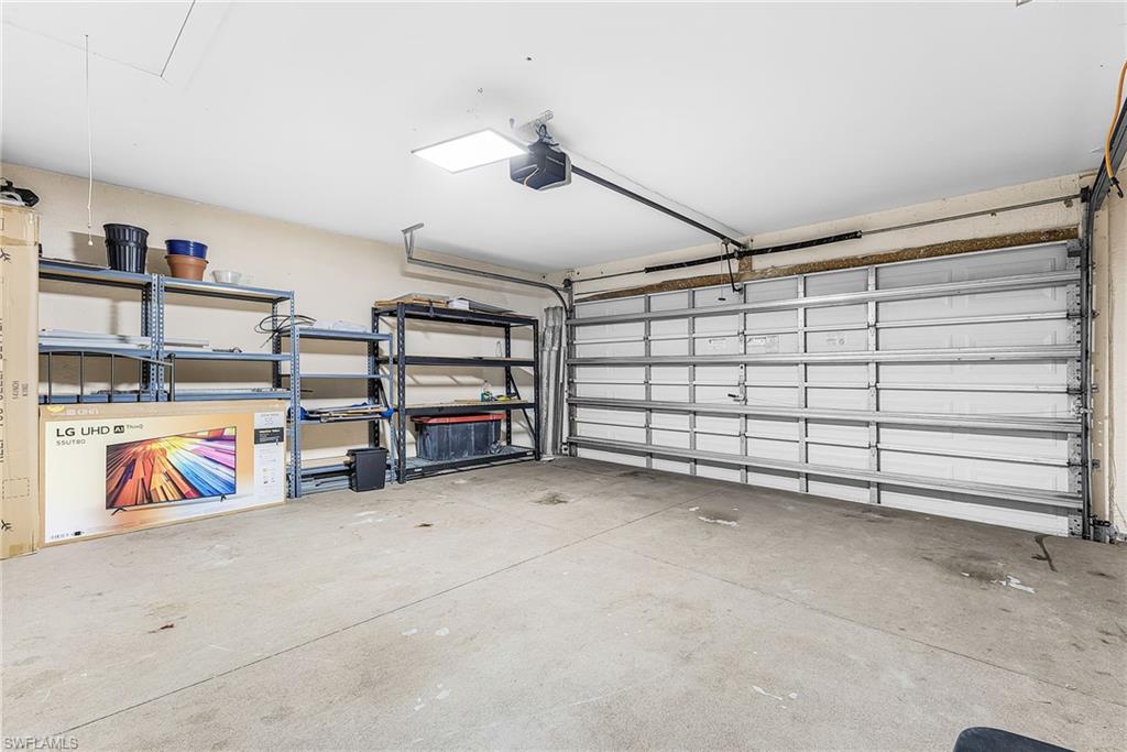 Attached garage with a concrete floor, overhead lighting, and an automatic garage door opener
