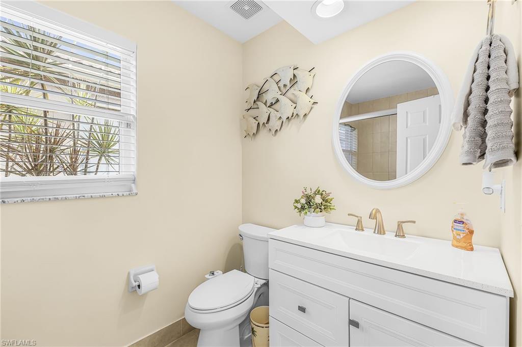 White vanity with a white countertop and brass-finish faucet