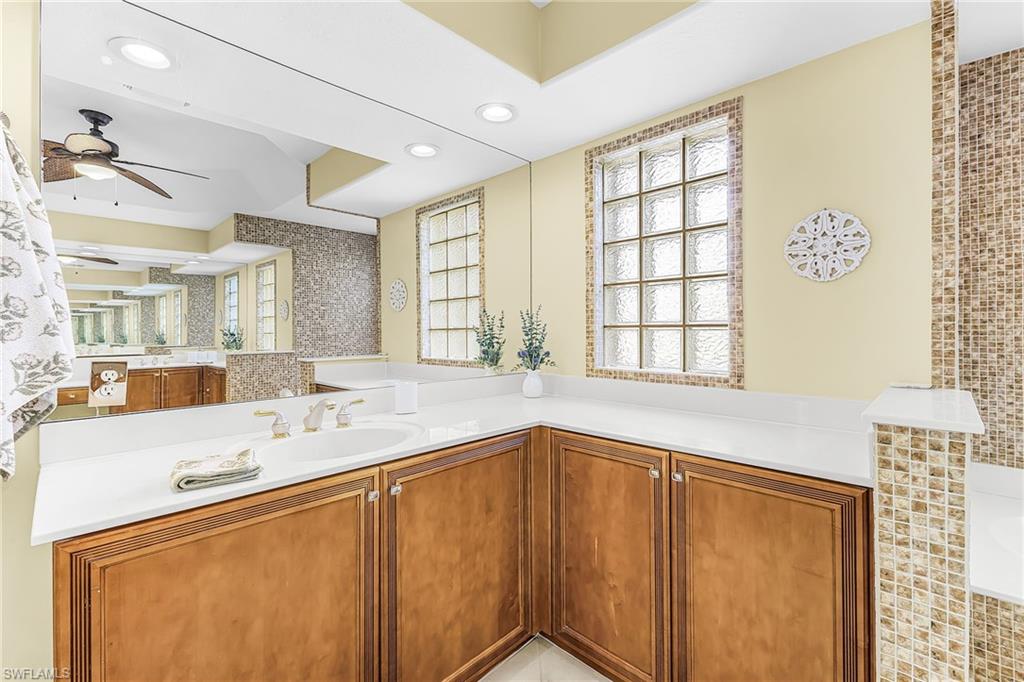Recessed lighting, wood-finish cabinetry, white countertop, integrated sink, and glass block window