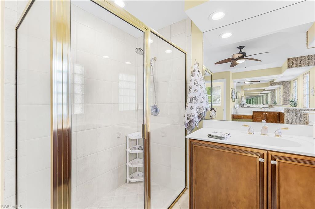 Glass-enclosed shower with gold-tone framing and white tile surround