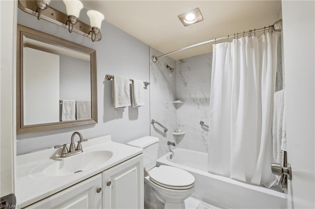 White vanity with integrated sink, brushed nickel faucet, framed mirror, and three-light fixture