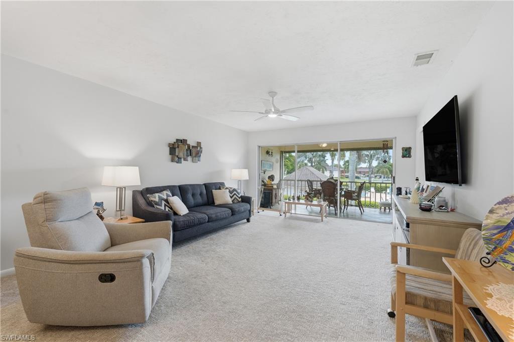 Carpeted living area with white walls and a ceiling fan