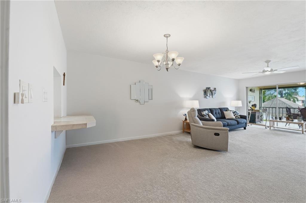 Spacious living area featuring neutral carpeting, a built-in stone-finish countertop, and a ceiling fan