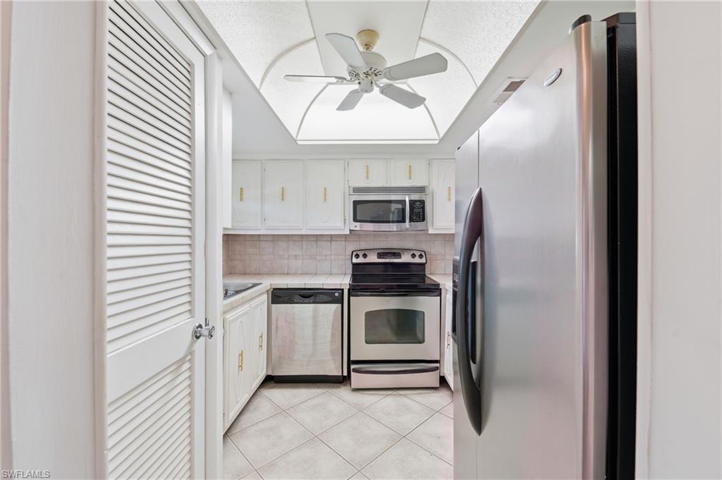 Kitchen featuring stainless steel appliances, white cabinetry, tile flooring, and a ceiling fan