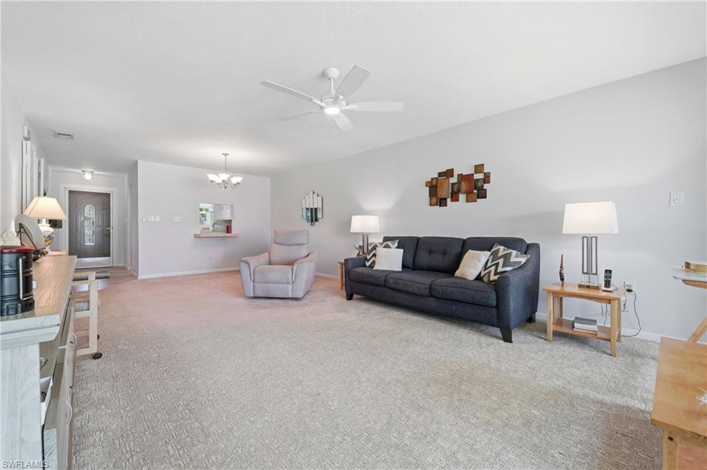 Open-concept living area with light-toned carpet flooring and a ceiling fan