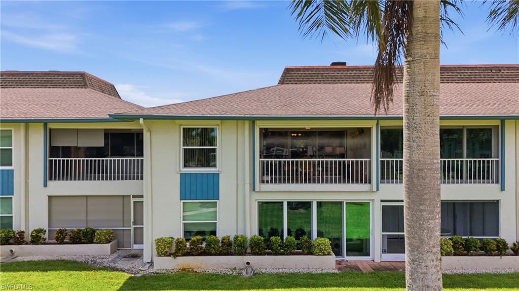 Two-story property featuring a tan exterior, multiple balconies with white railings, and sliding glass doors