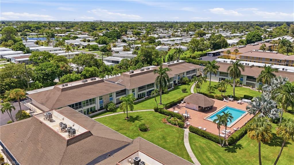 Expansive grounds featuring a pool with surrounding brick paving, a covered poolside structure, palm trees, and manicured lawns